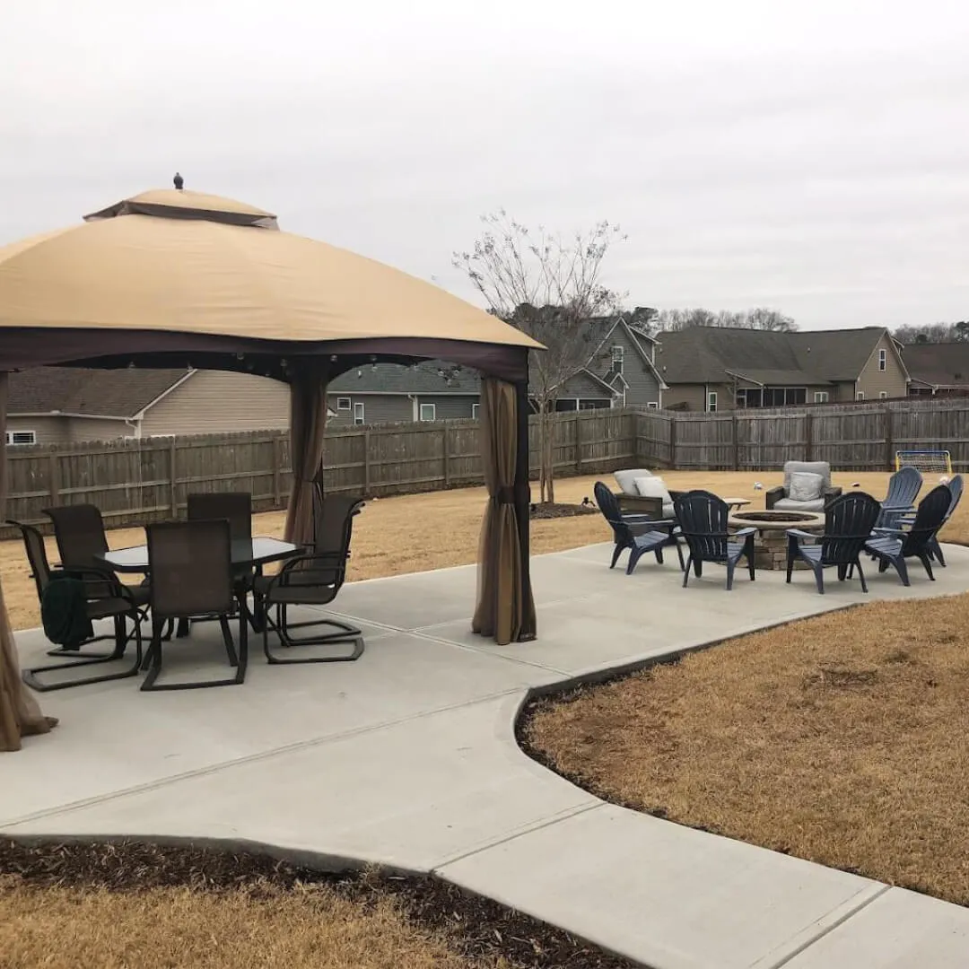 Outdoor patio with brick firepit and lounge chairs in a backyard